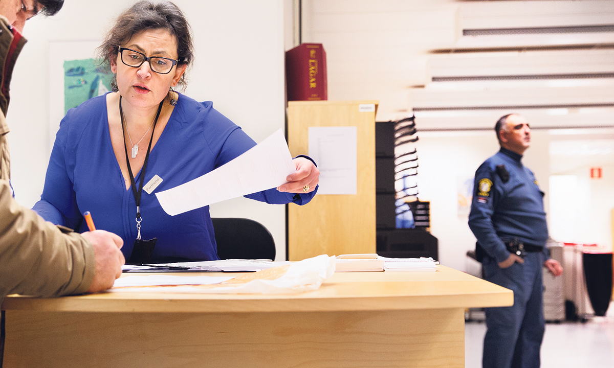 Parthena Forsberg tar emot en  besökare på Försäkringskassan.  I dag är det lugnt, men i bak­grunden finns en väktare till hands. »Jag skulle inte vilja komma hit och  arbeta utan dem«, säger hon.